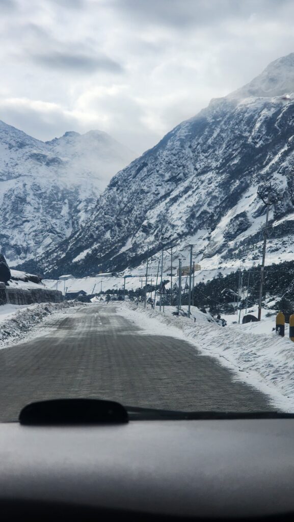 Snow-covered road at Sela Pass with scenic mountains, ideal for tailored travel packages