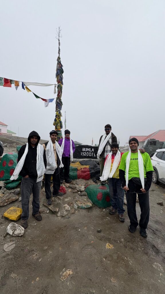 Travelers at Bumla Pass on a Sagamiles adventure, surrounded by mountains and prayer flags